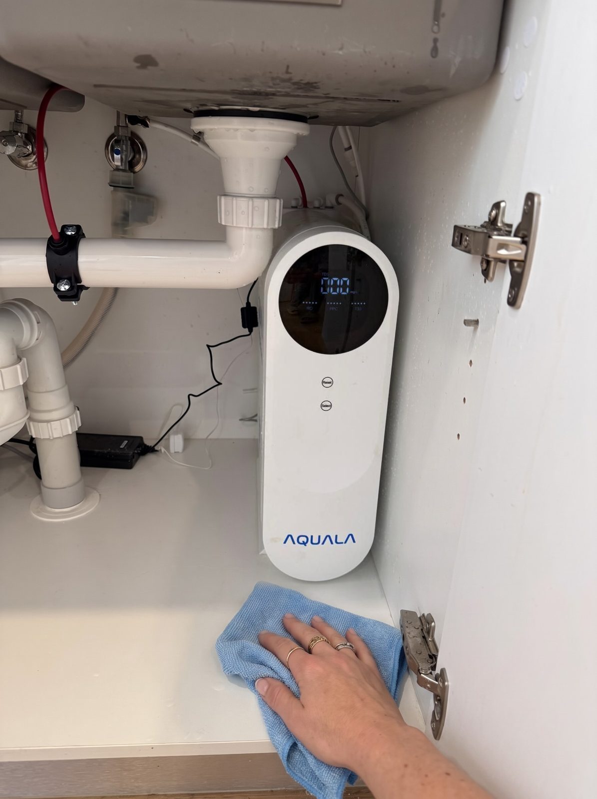 A hand wipes the shelf beside a P500 plugged into a power point under the sink.