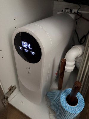 A customer's P500 in an under-sink cupboard beside a pipe and a roll of blue cloths.
