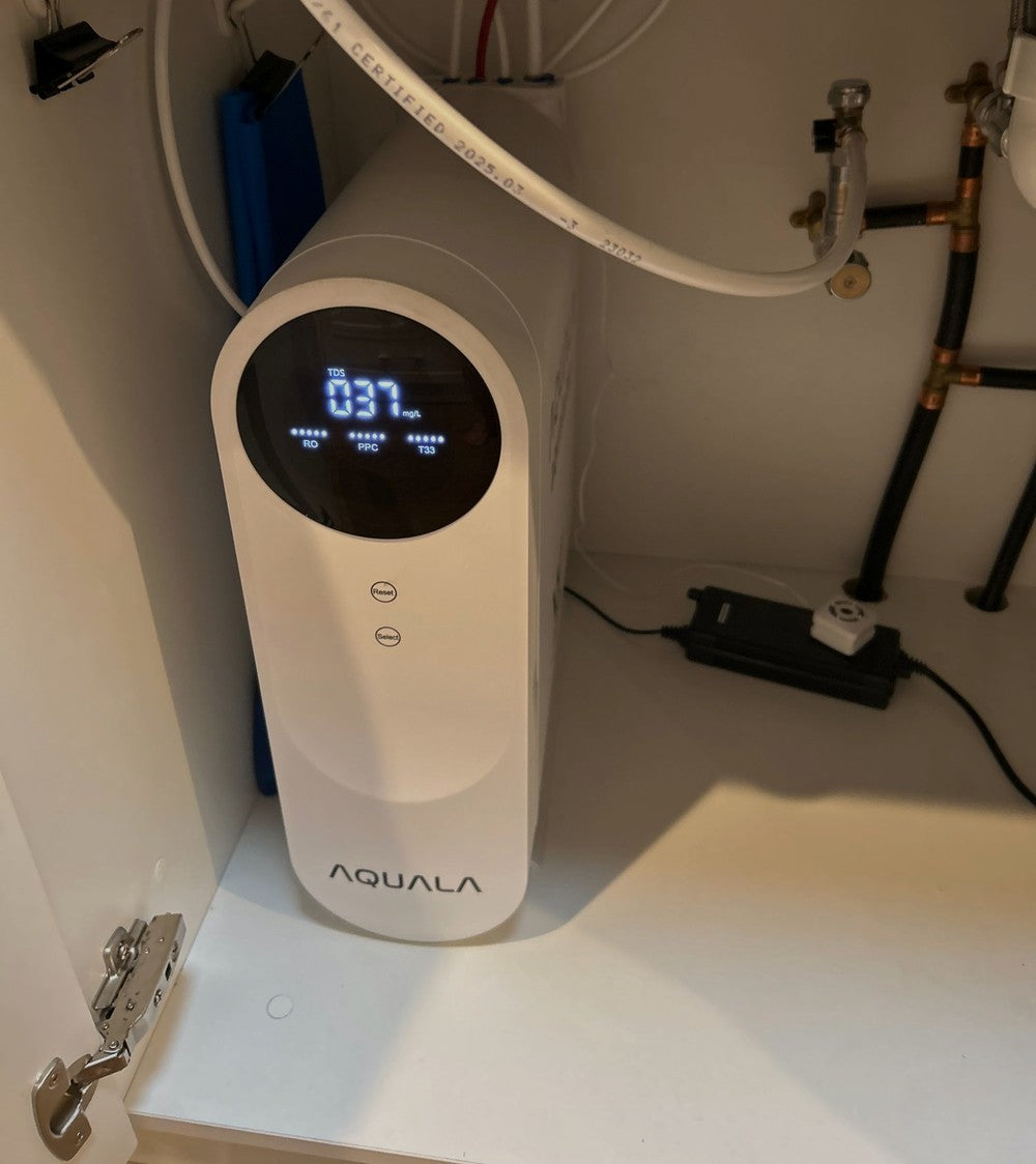 A P500 standing in an under-sink cupboard with its power adapter on the shelf beside it.